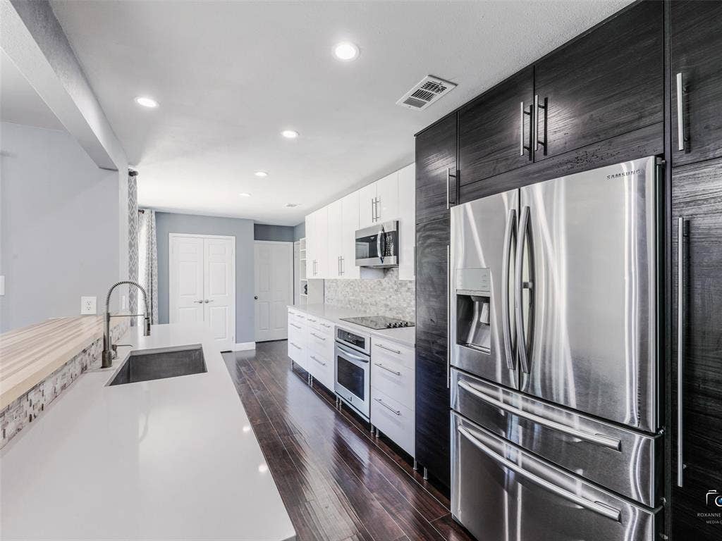 6701 Vero Drive, Plano, TX 75023 Modern updated kitchen featuring dark wood-finish flooring, quartz-style counters, stone backsplash and recessed lighting. Fridge to convey with the property.