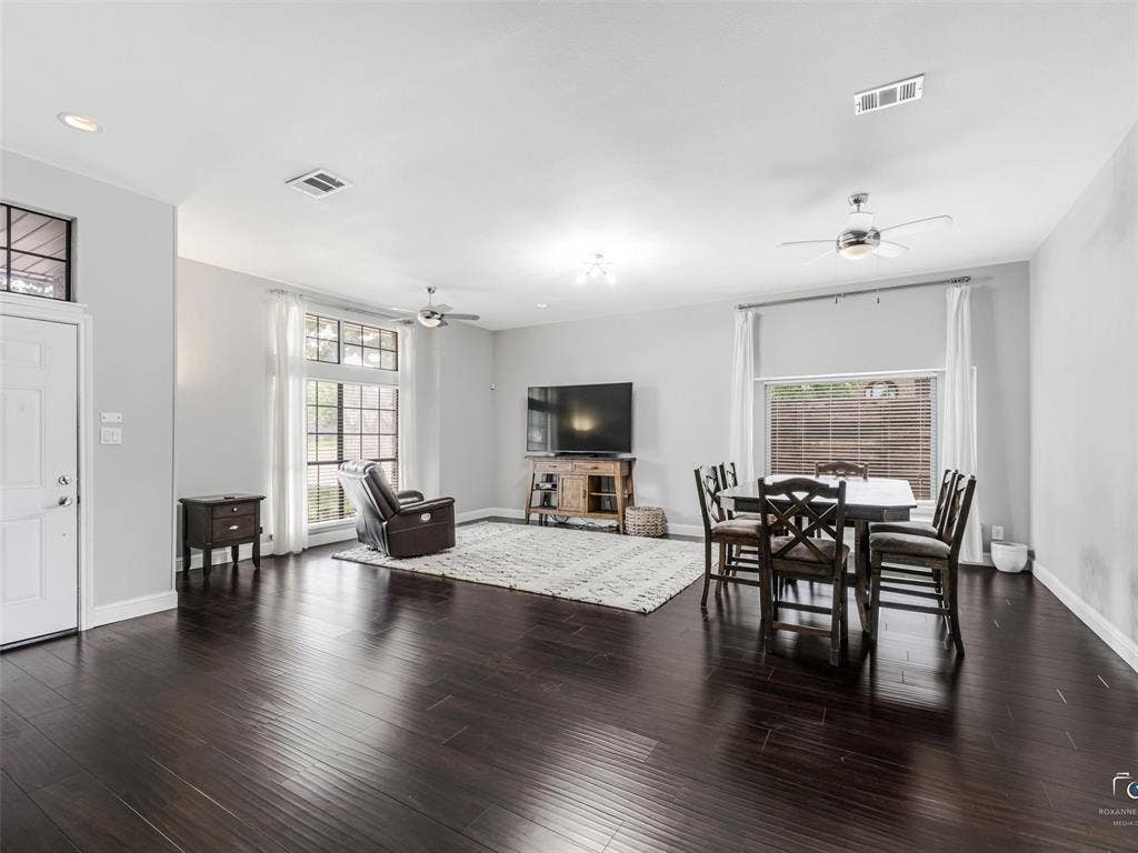 6701 Vero Drive, Plano, TX 75023 Open-concept living space features a living area and dining area with wood flooring, light gray walls, recessed lighting, two multiple ceiling fans and large windows providing ample natural light.