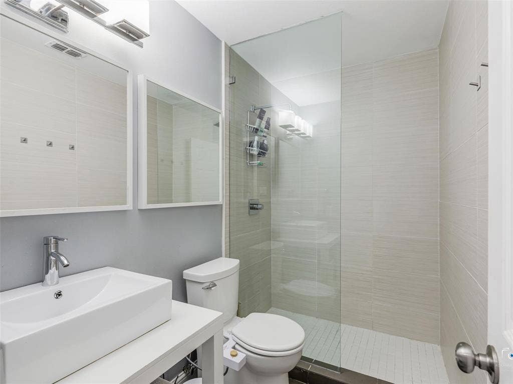 6701 Vero Drive, Plano, TX 75023 Bathroom two featuring a glass-enclosed shower, and floor to ceiling tile shower surround, and a rectangular vessel sink with a chrome faucet