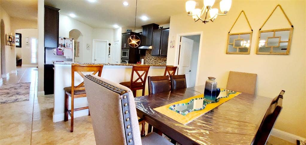104 Rustic Oak Lane, McKinney, TX 75072 Dining area featuring a chandelier, a dark wood-finish table, and a neutral-toned upholstered chair