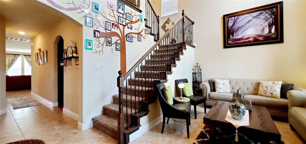 104 Rustic Oak Lane, McKinney, TX 75072 Grandiose two-story entry with a carpeted staircase featuring wrought iron balusters and a dark wood handrail