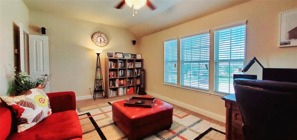 104 Rustic Oak Lane, McKinney, TX 75072 Room featuring a vaulted ceiling with a ceiling fan, three windows with blinds, built-in shelving, and carpet flooring