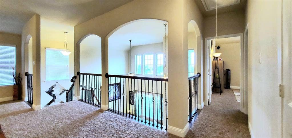 104 Rustic Oak Lane, McKinney, TX 75072 Upper-level landing featuring neutral carpeting, arched doorways, and wrought iron balusters