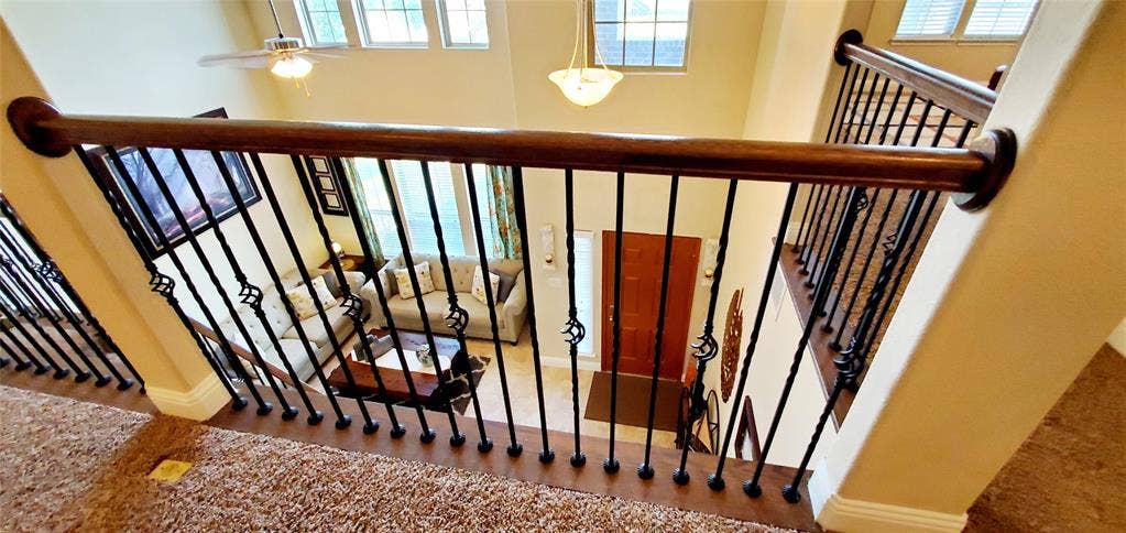 104 Rustic Oak Lane, McKinney, TX 75072 Upper-level landing featuring a wood handrail with decorative black iron balusters, overlooking a two-story foyer