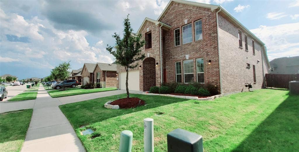 104 Rustic Oak Lane, McKinney, TX 75072 Brick exterior with multiple windows, an arched entryway, and a two-car garage