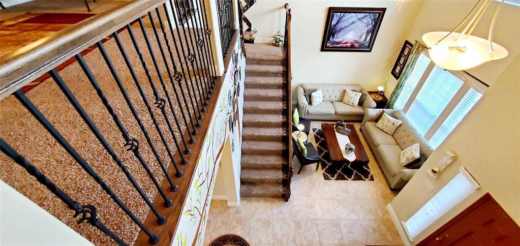 104 Rustic Oak Lane, McKinney, TX 75072 Grand entry featuring a two-story ceiling, a staircase with decorative wrought iron balusters and a wood handrail, and high-set windows