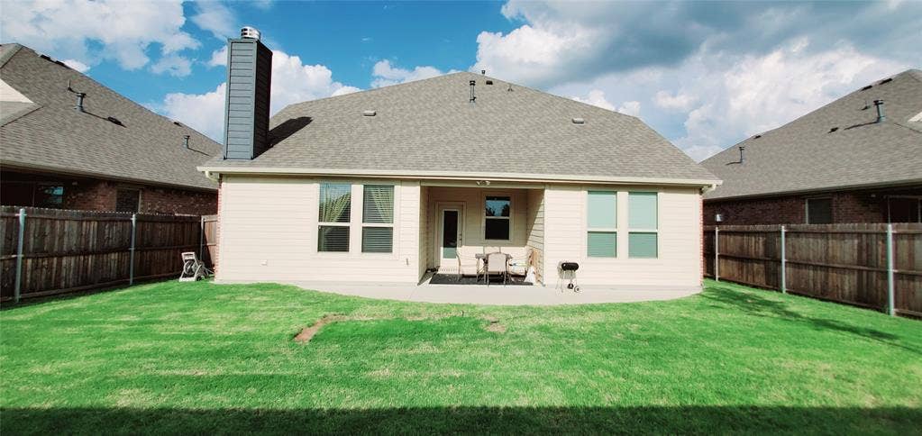 104 Rustic Oak Lane, McKinney, TX 75072 Expansive rear yard featuring a concrete patio, a full privacy fence, and a modern chimney