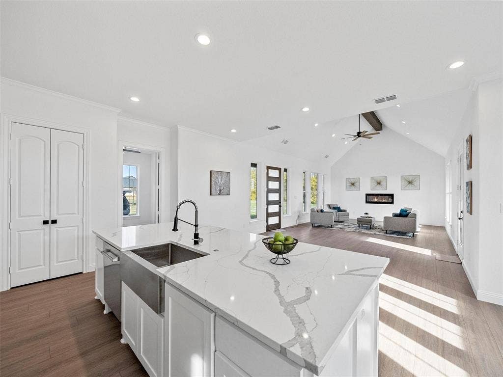1203 Chapel Drive, Rockwall, TX 75032 Kitchen island with a stainless steel farmhouse sink, quartz countertop, and dark-finish pull-down faucet