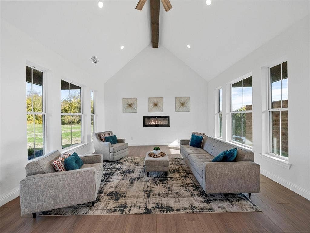 1203 Chapel Drive, Rockwall, TX 75032 Vaulted ceiling with exposed wood beam, recessed lighting, wood-finish flooring, built-in fireplace, and multiple tall windows