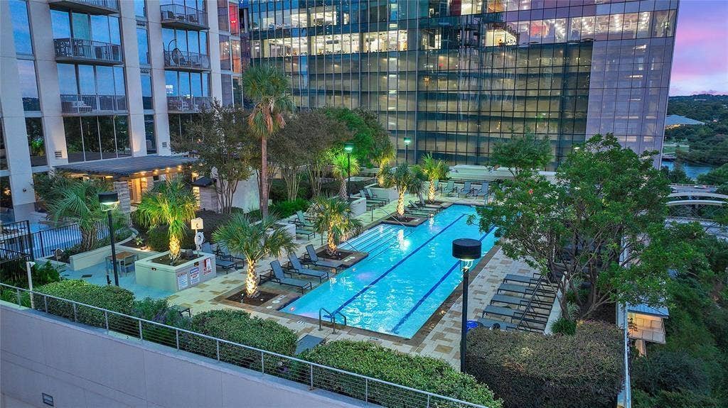 360 Nueces Street, #2110, Austin, TX 78701 Rooftop amenity deck featuring a lap pool with integrated lighting, surrounding paved patio, and mature palm trees