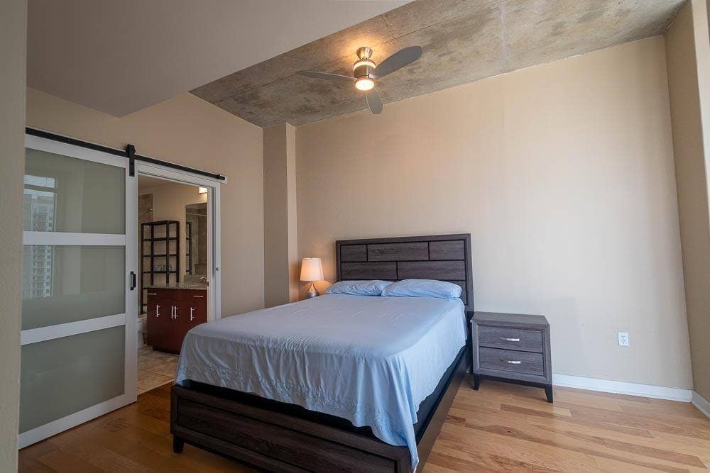 360 Nueces Street, #2110, Austin, TX 78701 Bedroom featuring a concrete ceiling, a ceiling fan with integrated lighting, and wood-finish flooring