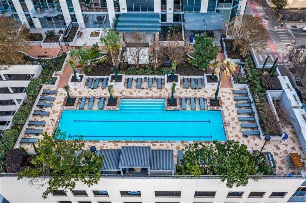 360 Nueces Street, #2110, Austin, TX 78701 Rooftop amenity deck featuring a lap pool with integrated steps, surrounding lounge chairs, various planters with mature foliage, and paving stone surfacing
