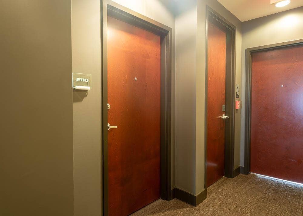 360 Nueces Street, #2110, Austin, TX 78701 Hallway featuring doors with brushed nickel hardware, neutral-toned walls, and textured carpet flooring