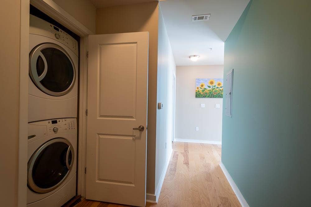 360 Nueces Street, #2110, Austin, TX 78701 Convenient laundry closet featuring a stacked white washer and dryer unit, complemented by wood-finish flooring and neutral wall tones