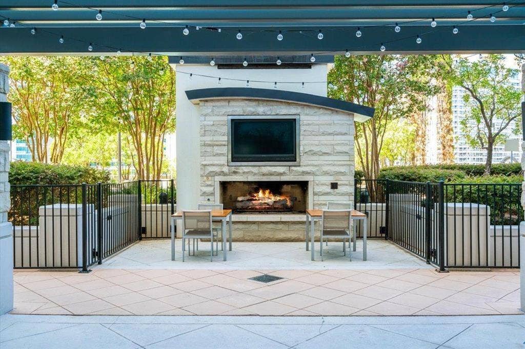 360 Nueces Street, #2110, Austin, TX 78701 Outdoor patio featuring a stone-clad fireplace with a built-in media niche, string lighting, and a durable tile floor