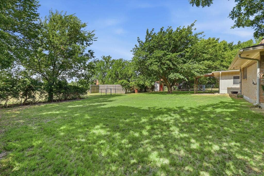 Expansive rear yard featuring a large grass lawn and mature trees