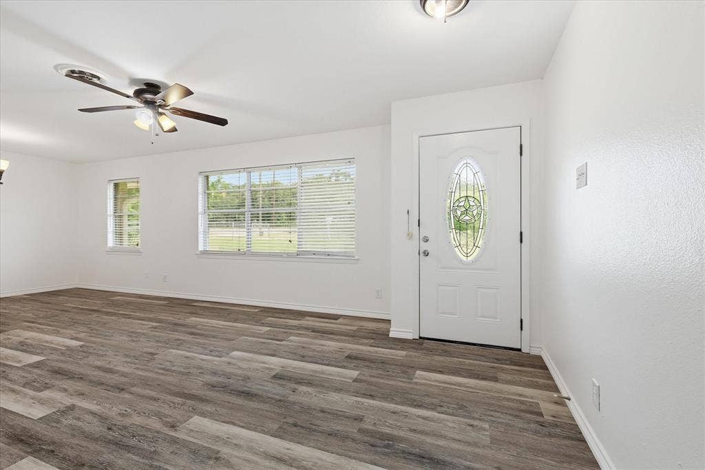 Entry foyer featuring a decorative glass-insert door, wood-finish flooring, and a ceiling fan with integrated lighting