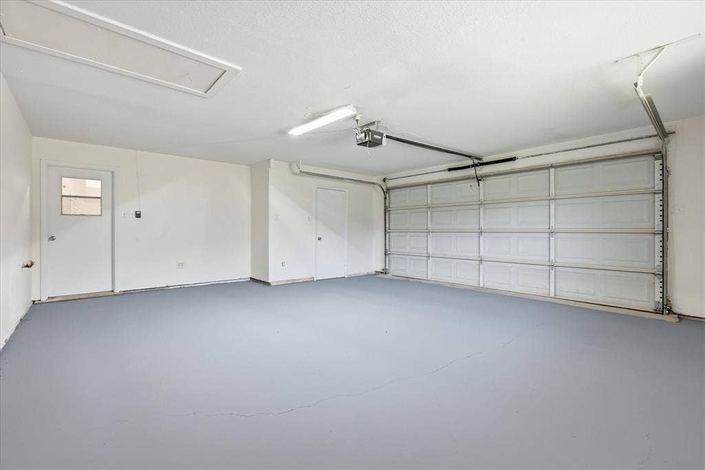 Spacious garage with light gray flooring and a paneled overhead garage door