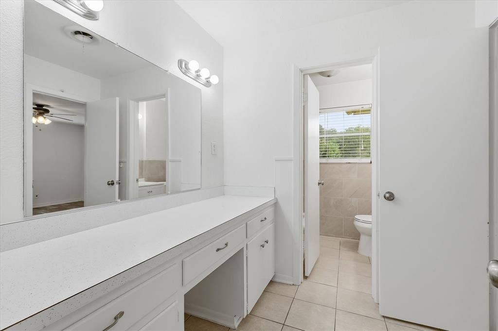 Vanity area featuring an expansive countertop, integrated mirror, and built-in cabinetry with drawers