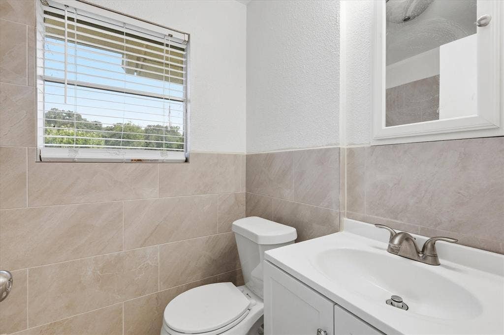 Bathroom featuring a white vanity with an integrated sink, brushed nickel faucet, and a wall-mounted medicine cabinet