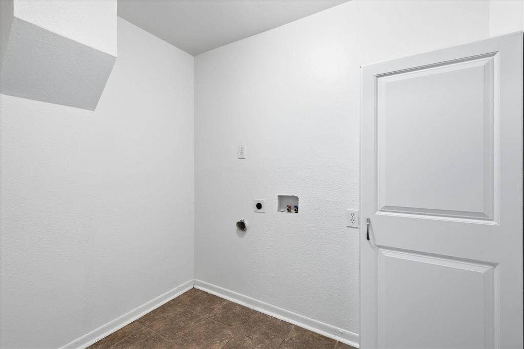 Utility area featuring neutral wall paint, a panel door, baseboard trim, and tile-finish flooring