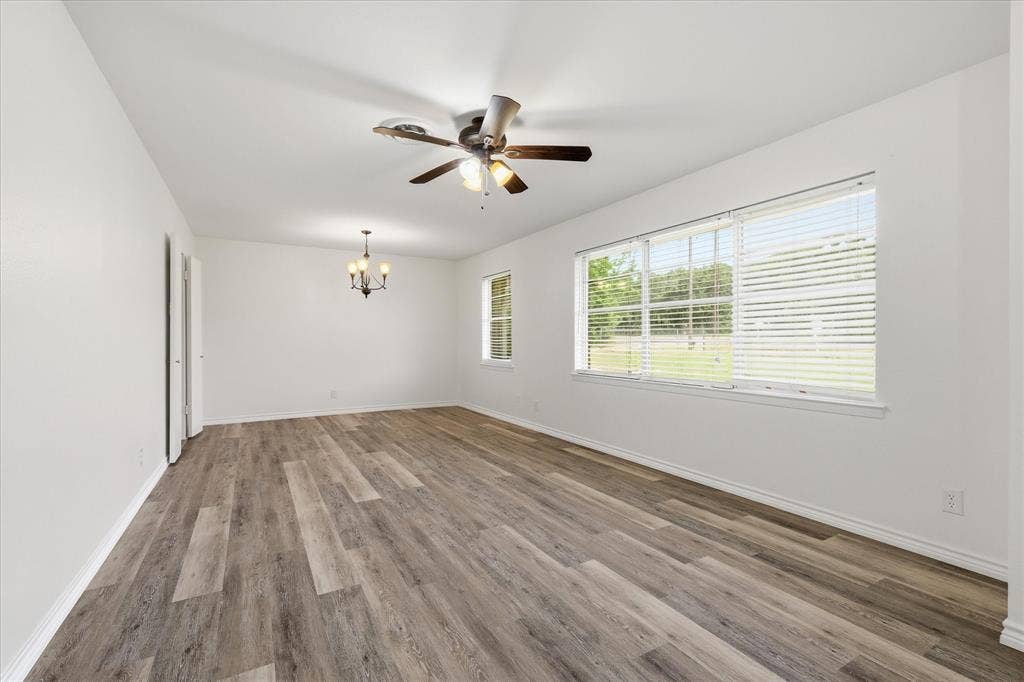 Expansive living area featuring wide plank wood-finish flooring, white walls, and abundant natural light from multiple windows