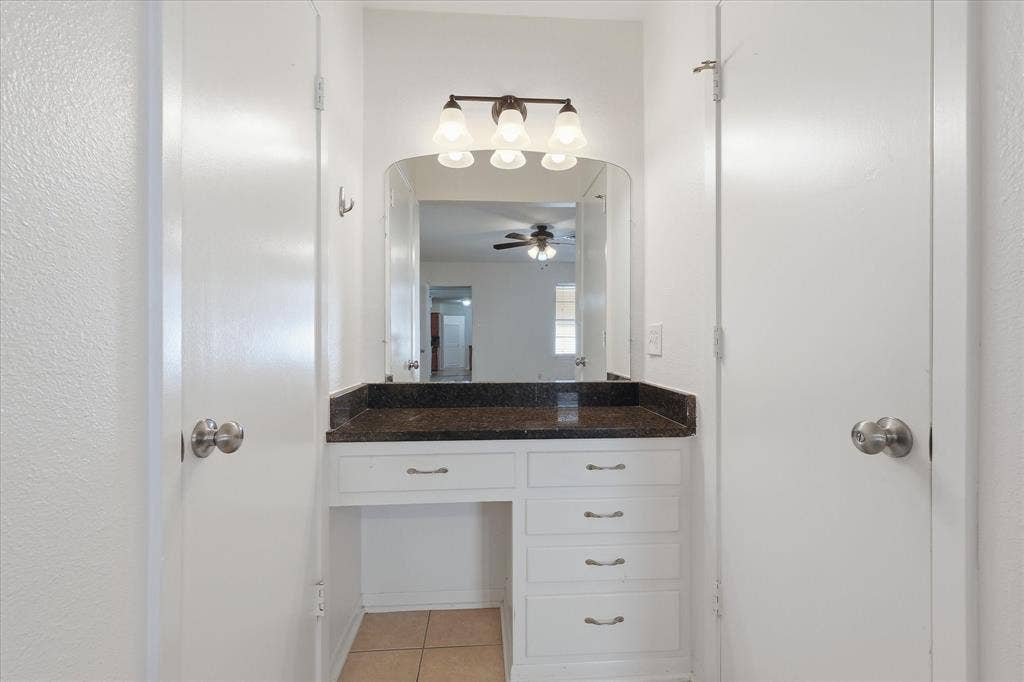 Vanity area featuring a dark countertop, integrated mirror, and bronze-finish light fixture