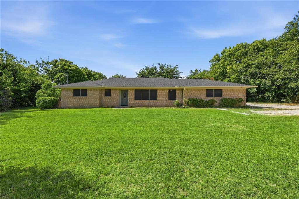 Single-story brick residence featuring a dark shingled roof and a light-colored entry door