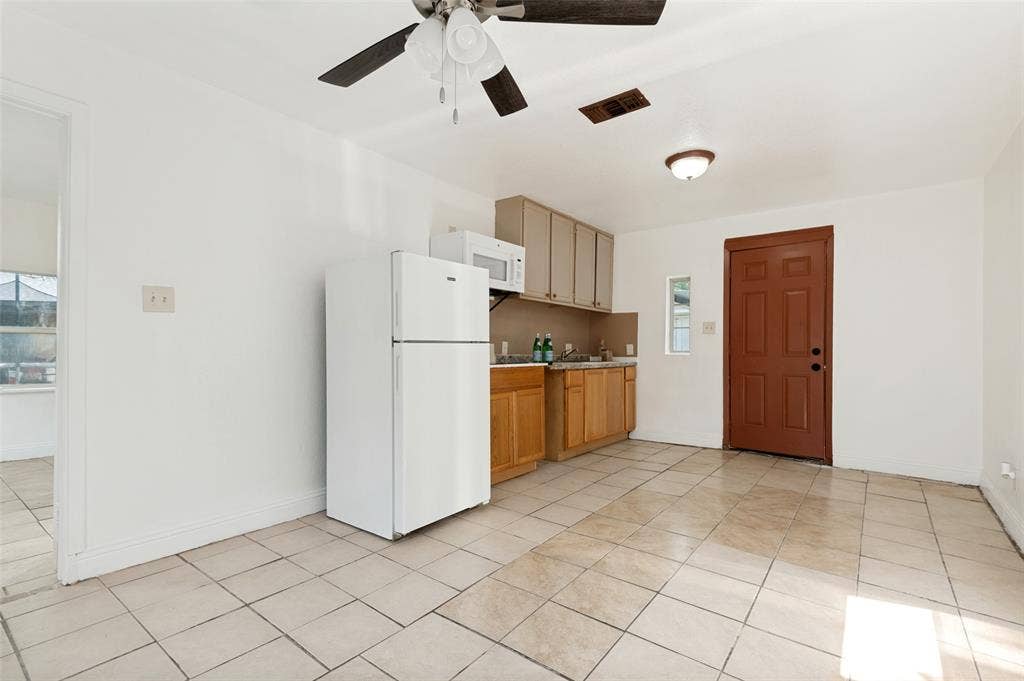 403 N Britain Road, #407B, Irving, TX 75061 Tile flooring with a compact kitchen featuring wood-finish lower cabinetry, light-colored upper cabinetry, and a ceiling fan