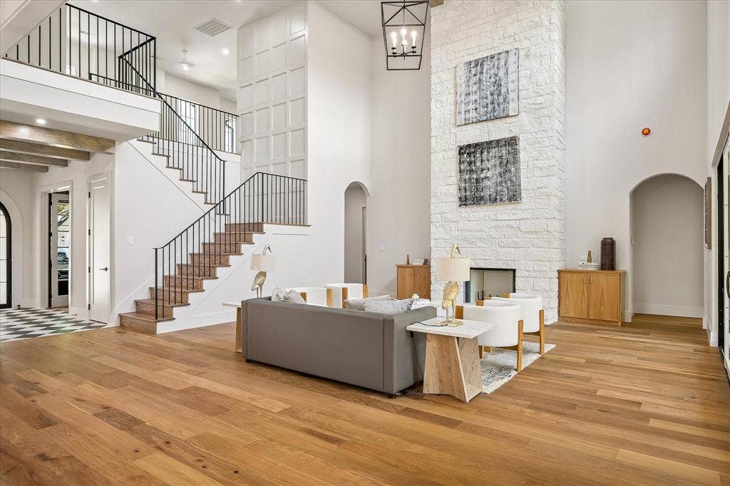 3304 Townsend Drive, Dallas, TX 75229 Two-story living room, floor-to-ceiling stone fireplace, iron stair railing, wide plank hardwood floors