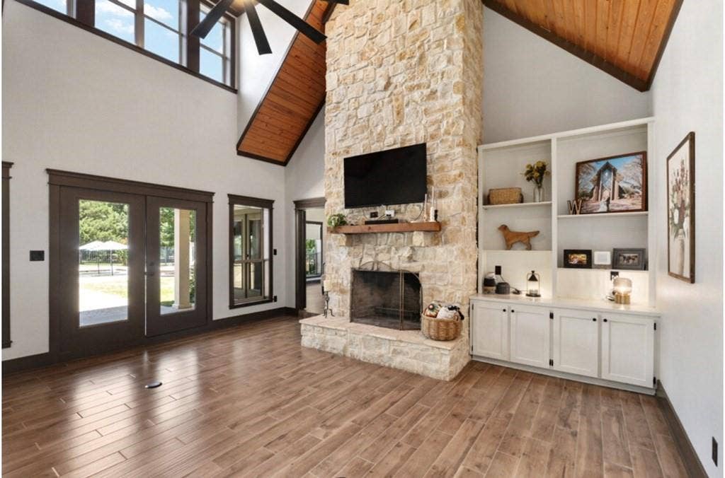 106 Timber Hill, Athens, TX 75751 Great room featuring a floor-to-ceiling stone fireplace, high vaulted ceilings with wood paneling, wood-finish flooring, built-in shelving, and French doors