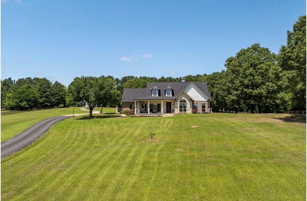 106 Timber Hill, Athens, TX 75751 Exterior featuring a stone and brick facade, a covered front porch with white columns, and a dormer window roofline