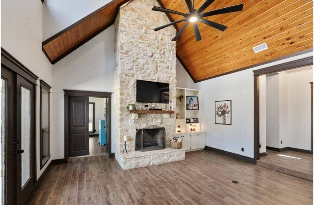 106 Timber Hill, Athens, TX 75751 Spacious living area featuring a stone fireplace, wood-finish flooring, and a vaulted wood-paneled ceiling with an exposed beam
