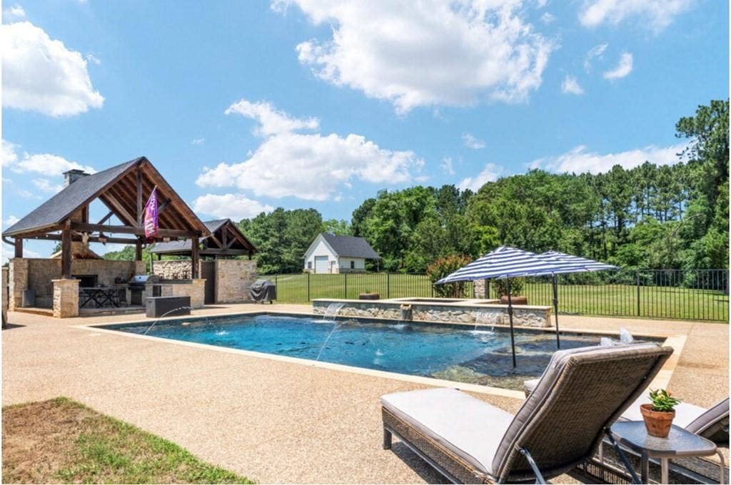 106 Timber Hill, Athens, TX 75751 Resort-style outdoor area featuring a custom pool with water features, an expansive patio, and an outdoor kitchen with a stone-clad structure and a covered dining area