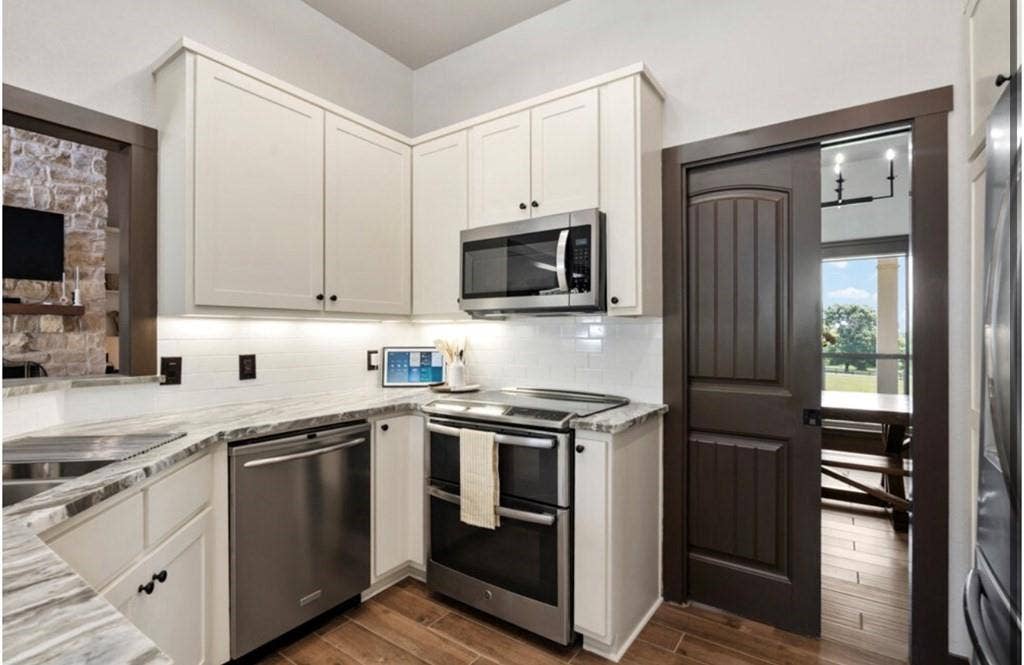 106 Timber Hill, Athens, TX 75751 Kitchen featuring white shaker cabinetry, stainless steel appliances, a white subway tile backsplash, and light-toned stone countertops