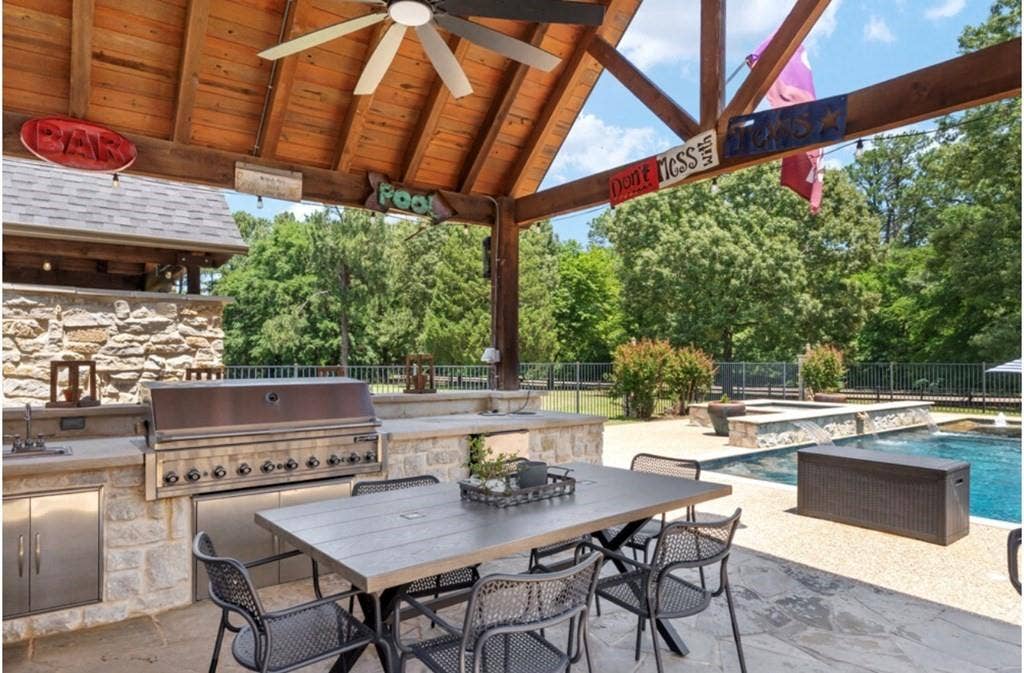 106 Timber Hill, Athens, TX 75751 Covered outdoor entertaining area featuring a wood-beam ceiling, built-in stainless steel grill, stone-clad outdoor kitchen, and a ceiling fan