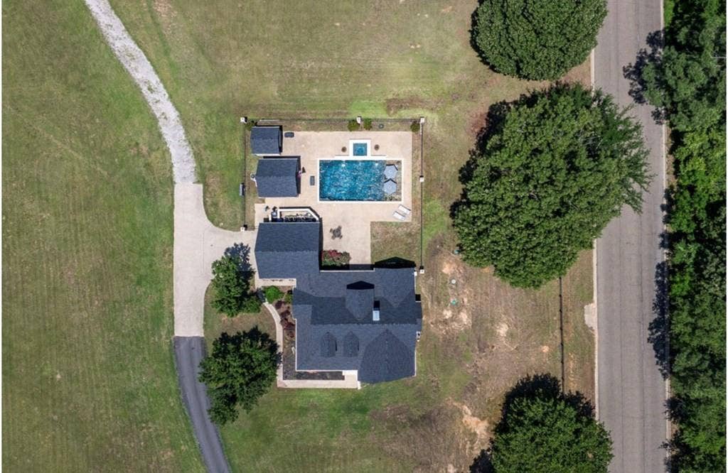 106 Timber Hill, Athens, TX 75751 Expansive property featuring a dark-roofed residence with multiple gables, a paved driveway, and a large inground pool surrounded by concrete decking