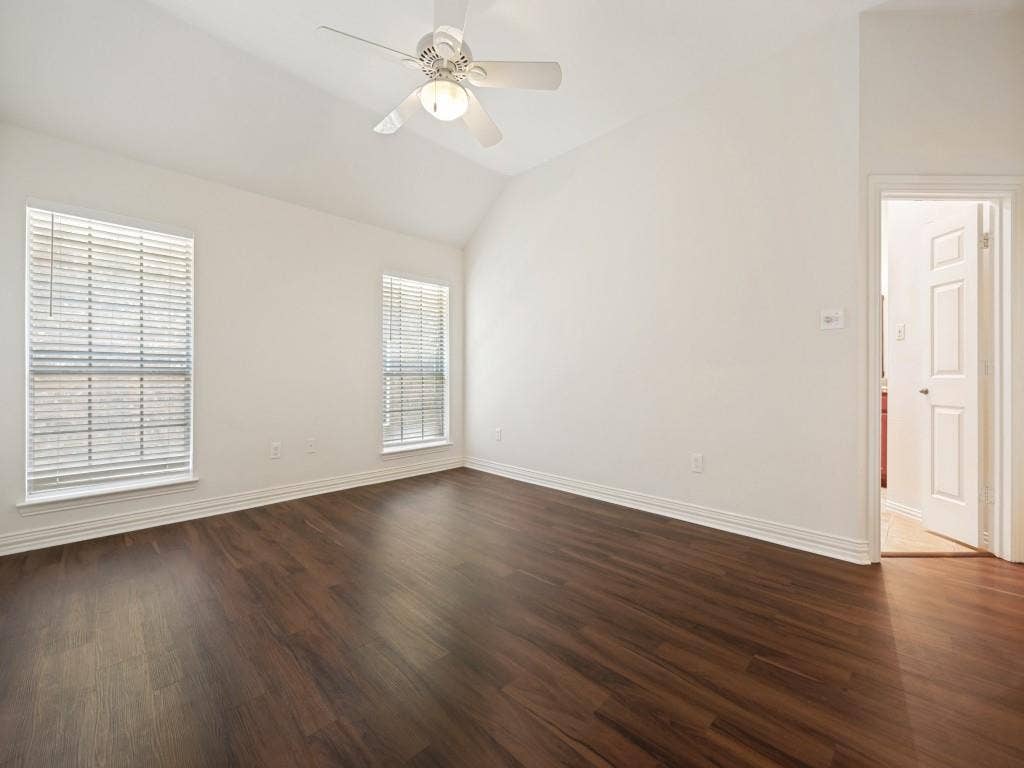 9703 Raven Lane, Irving, TX 75063 Spacious interior room featuring wood-finish flooring, white baseboards, and a vaulted ceiling with a ceiling fan