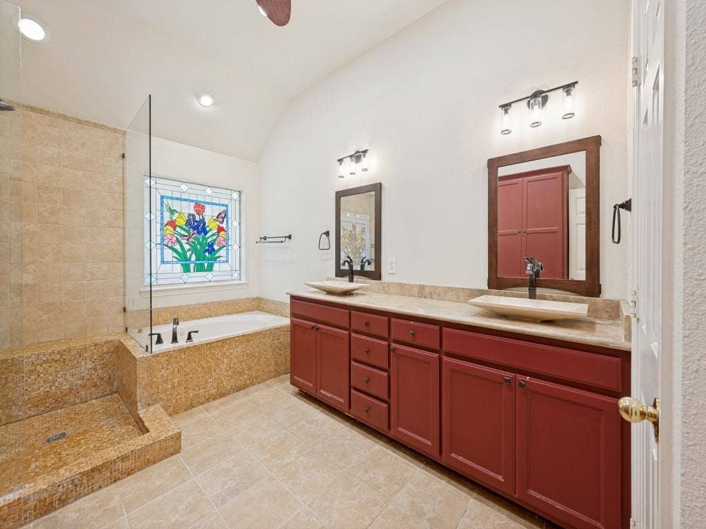 9703 Raven Lane, Irving, TX 75063 Bathroom featuring a dual vanity with vessel sinks, wood-finish cabinetry, and a large soaking tub