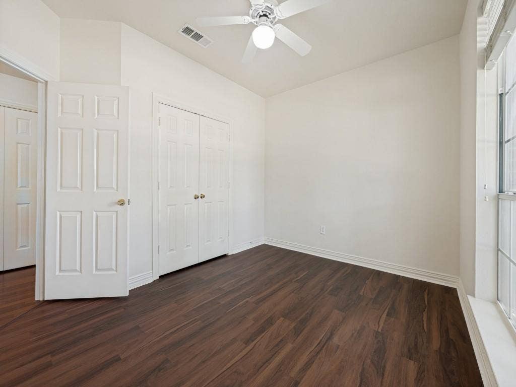 9703 Raven Lane, Irving, TX 75063 Room featuring wood-finish flooring, a ceiling fan with integrated lighting, a built-in closet with bifold doors, and an additional paneled door