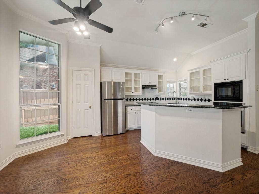 9703 Raven Lane, Irving, TX 75063 Kitchen featuring wood-finish flooring, white cabinetry, black countertops, and a built-in microwave