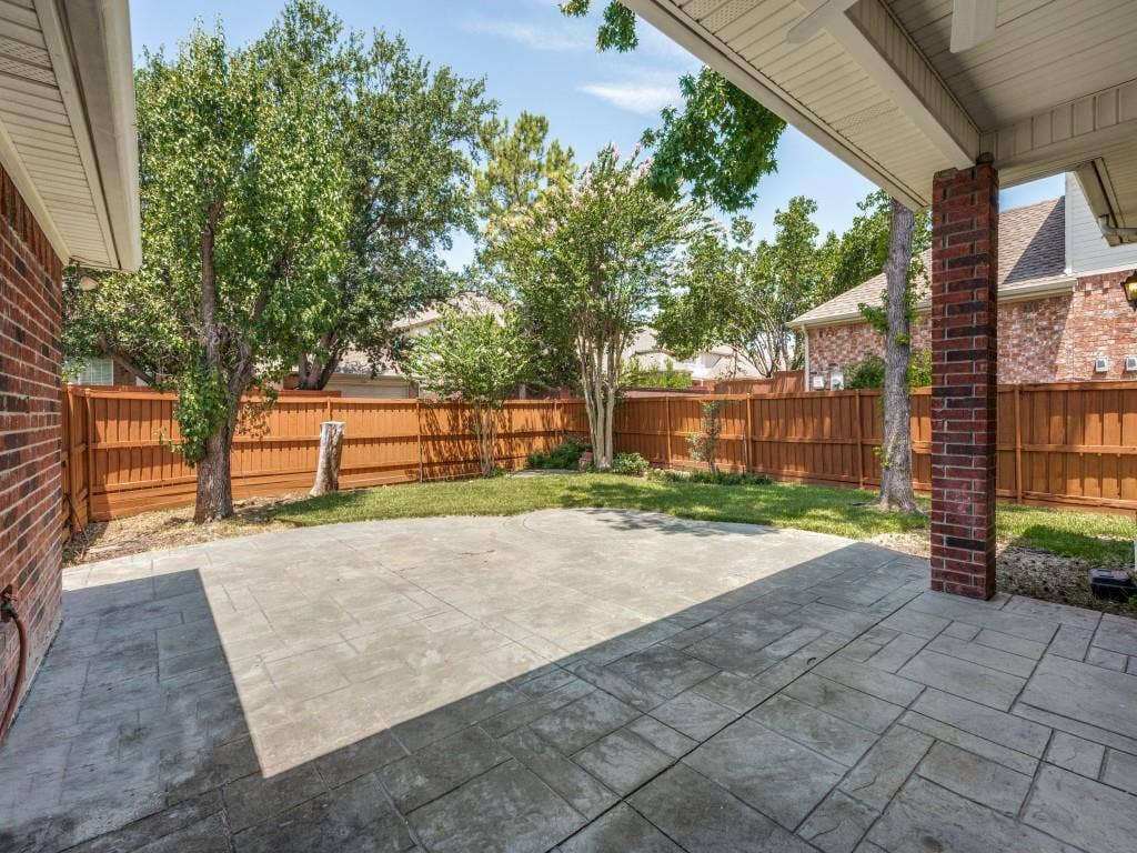 9703 Raven Lane, Irving, TX 75063 Expansive stamped concrete patio with architectural brick columns and a full privacy fence