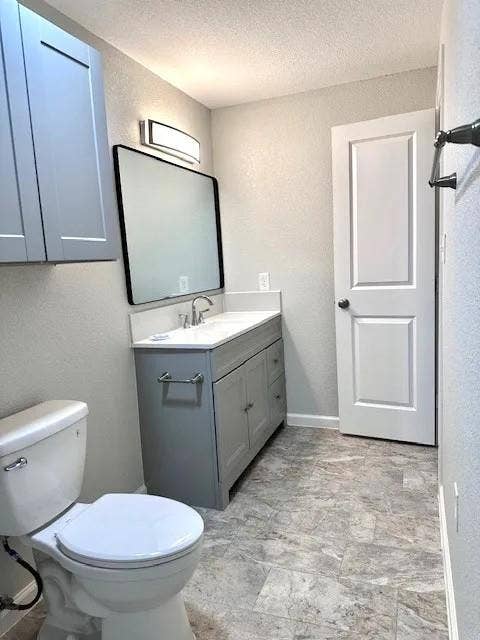 5280 Atwell Lane, #B, Denton, TX 76208 Contemporary bathroom featuring a grey vanity with a white countertop and integrated sink, a rectangular framed mirror, and a modern vanity light fixture