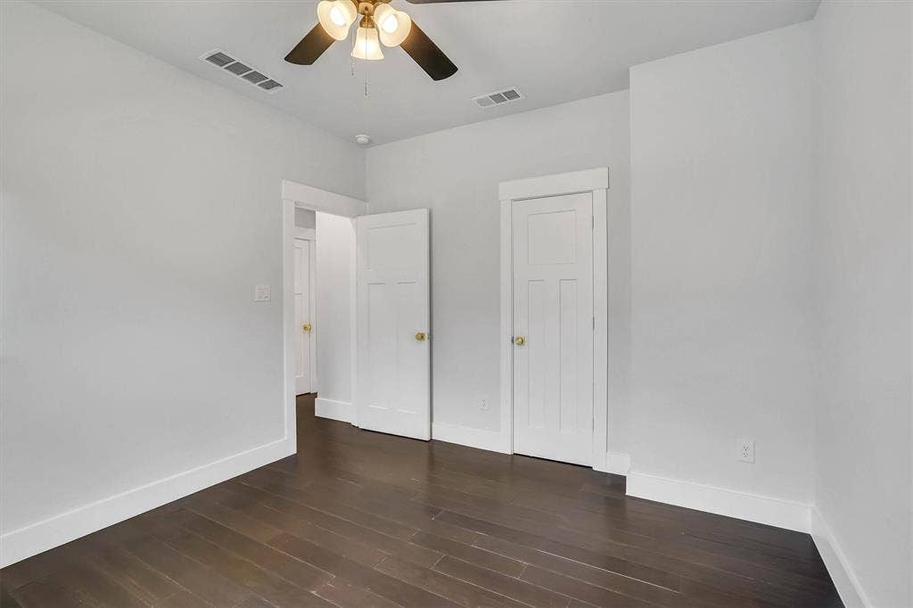 Interior room featuring dark wood-finish flooring, white baseboards, and light gray walls