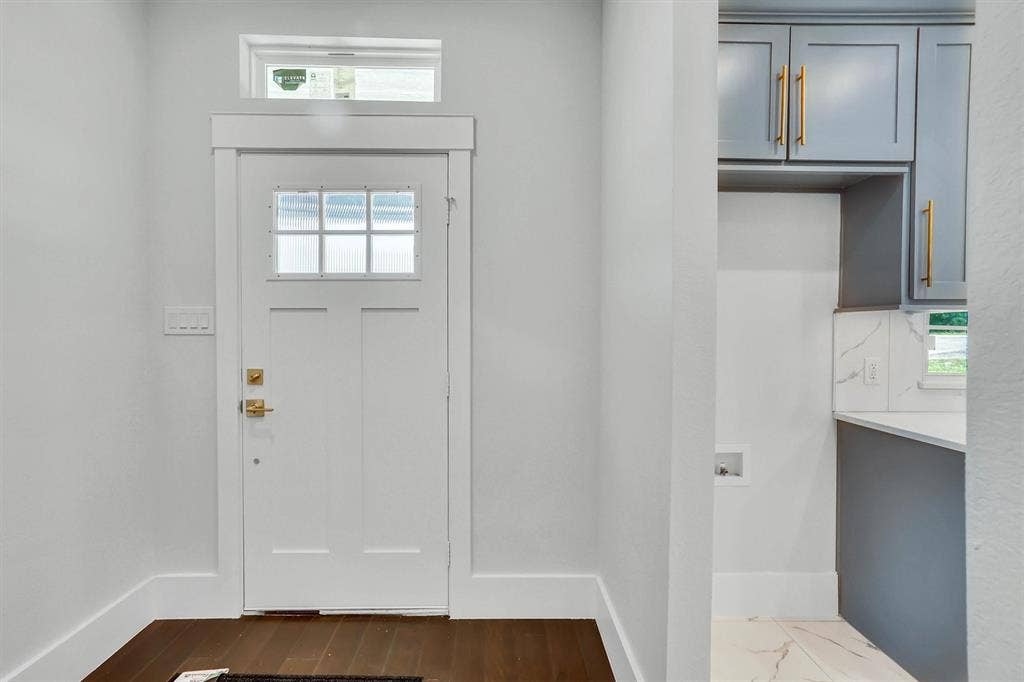 White paneled entry door with transom reeded glass window and brushed brass hardware