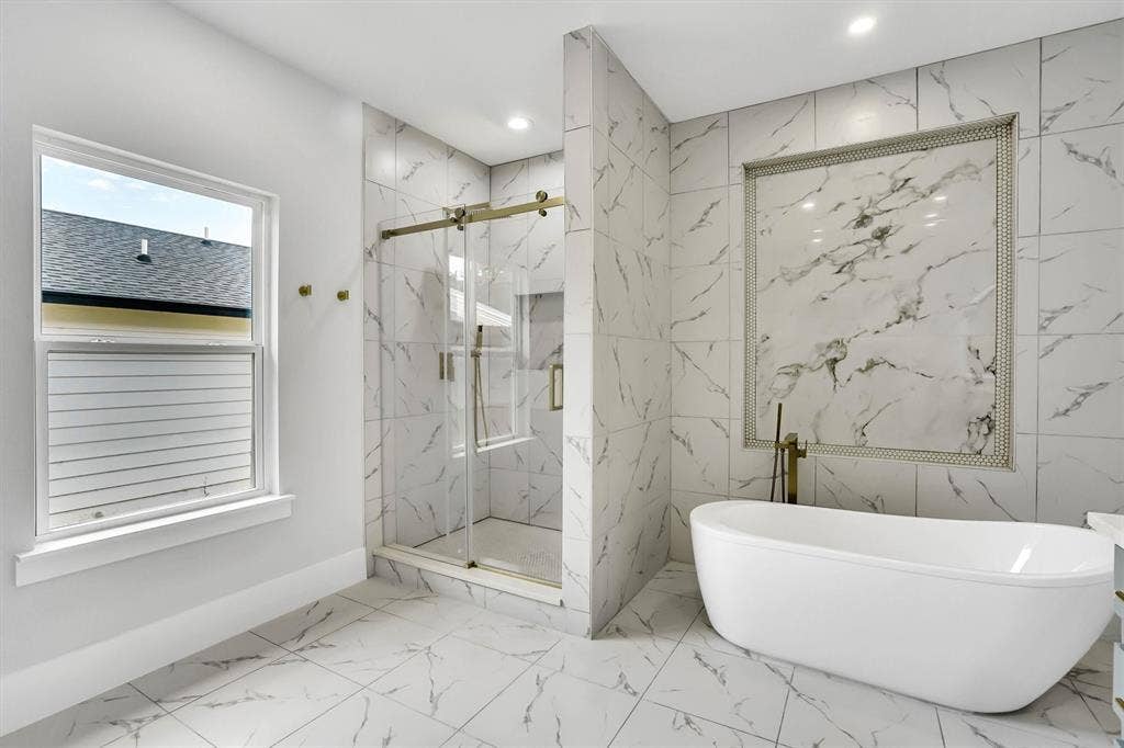 Freestanding soaking tub with a wall-mounted brass fixture