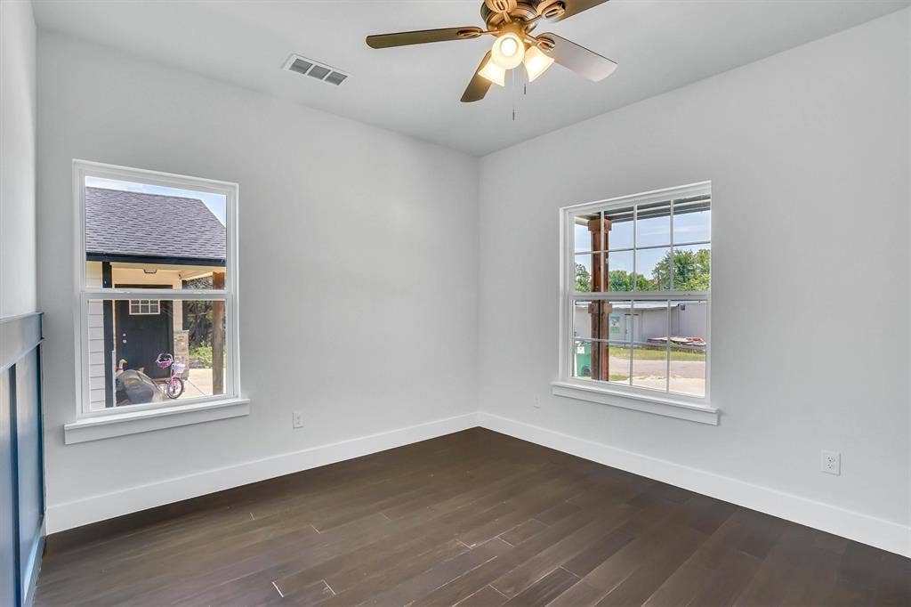 Bright interior featuring dark wood-finish flooring, white walls, and a ceiling fan with integrated lighting