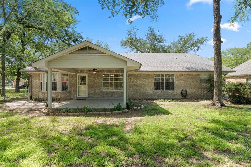 116 Meadowood Road, Enchanted Oaks, TX 75156 Brick exterior home featuring a covered patio, additional concrete patio area, and mature trees