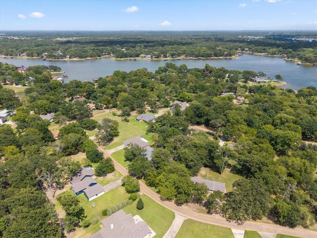 116 Meadowood Road, Enchanted Oaks, TX 75156 Expansive lakefront community featuring mature trees and a clear blue sky