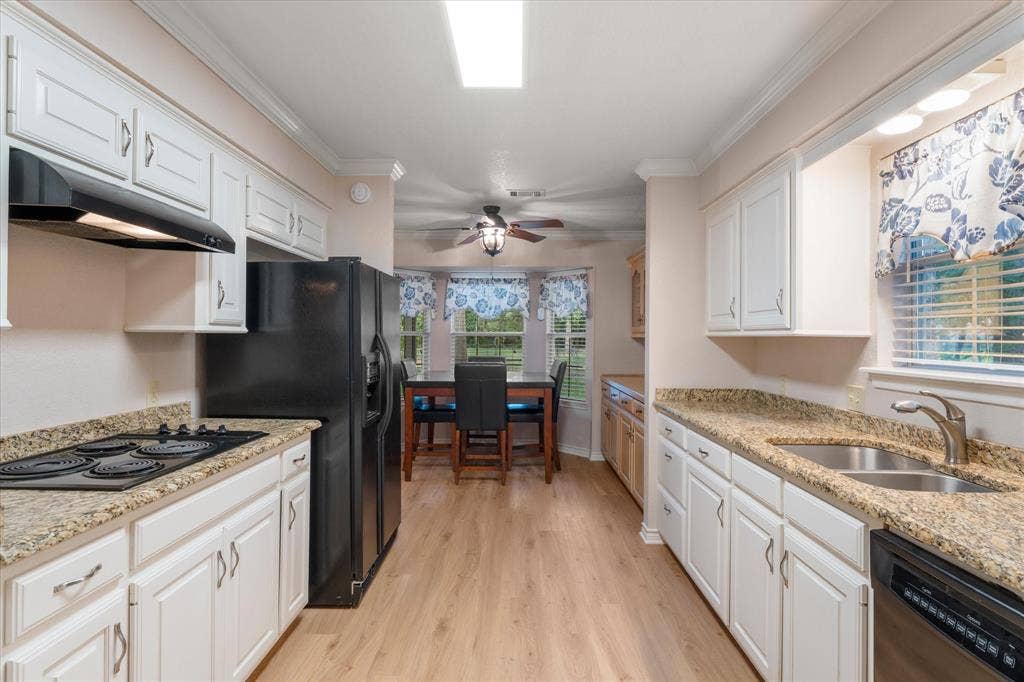 116 Meadowood Road, Enchanted Oaks, TX 75156 Galley kitchen featuring light wood-finish flooring, white cabinetry, and granite-patterned countertops